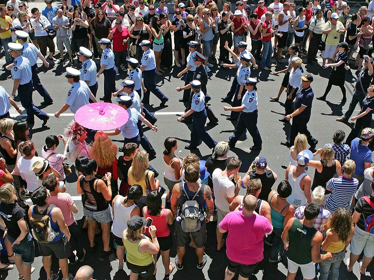 Police marching surrounded by a crowd at the Midsumma Pride March in St Kilda