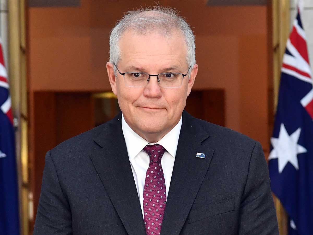 Scott Morrison in a suit in front of two Australian flags