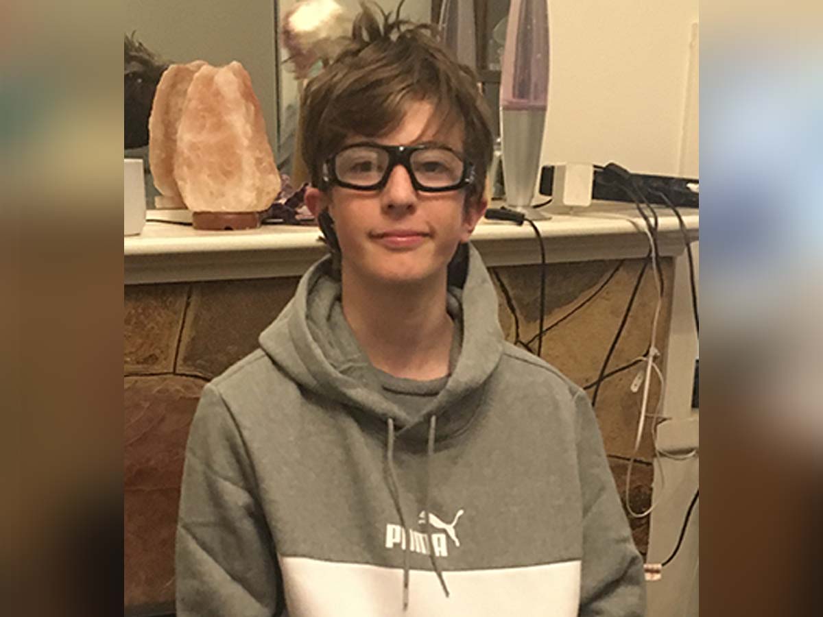 Thirteen year old boy with glasses smiling and looking at camera in new puma jumper