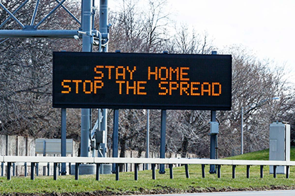 Sign on roadside which says 'stay home, stop the spread'