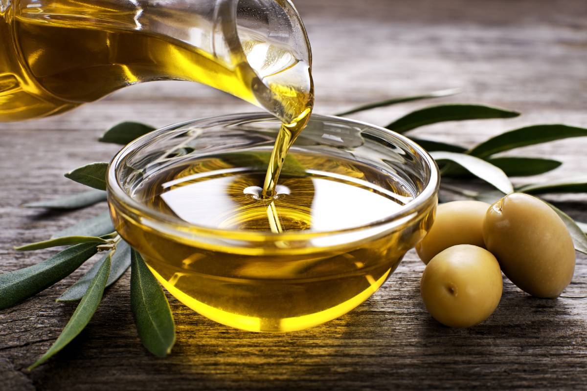 Jug of olive oil being poured into a dish