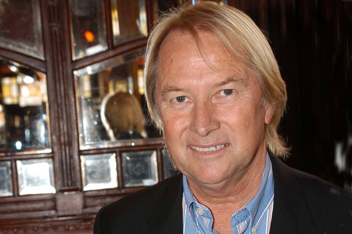 Glenn Wheatley smiles at the camera in a blue shirt and black suit