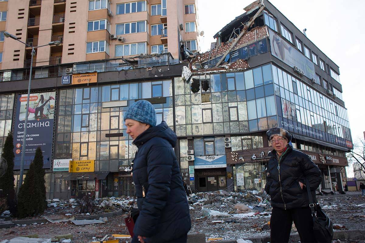 Two women walk past ruined Kyiv apartment building which was hit by a missile