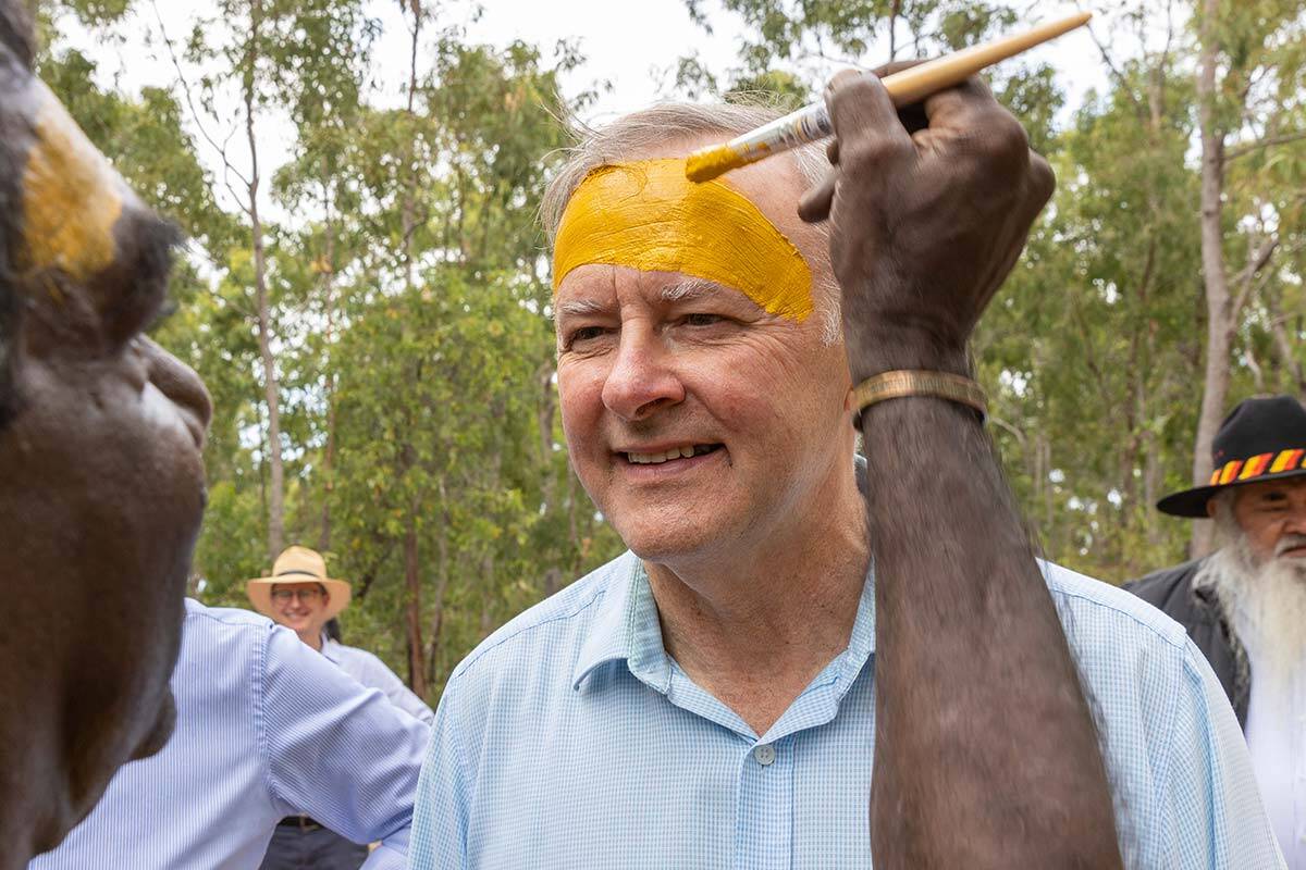 An Aboriginal man paints Anthony Albanese's forehead with yellow paint