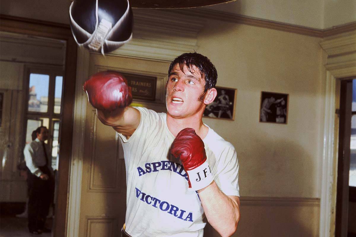 John Famechon in boxing gloves, hitting a punching bag