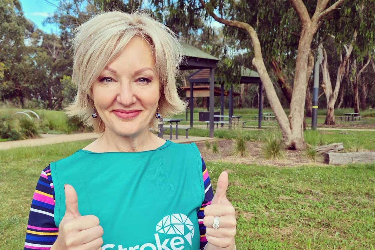 Heidi Victoria in a green vest, standing in a park with two thumbs up