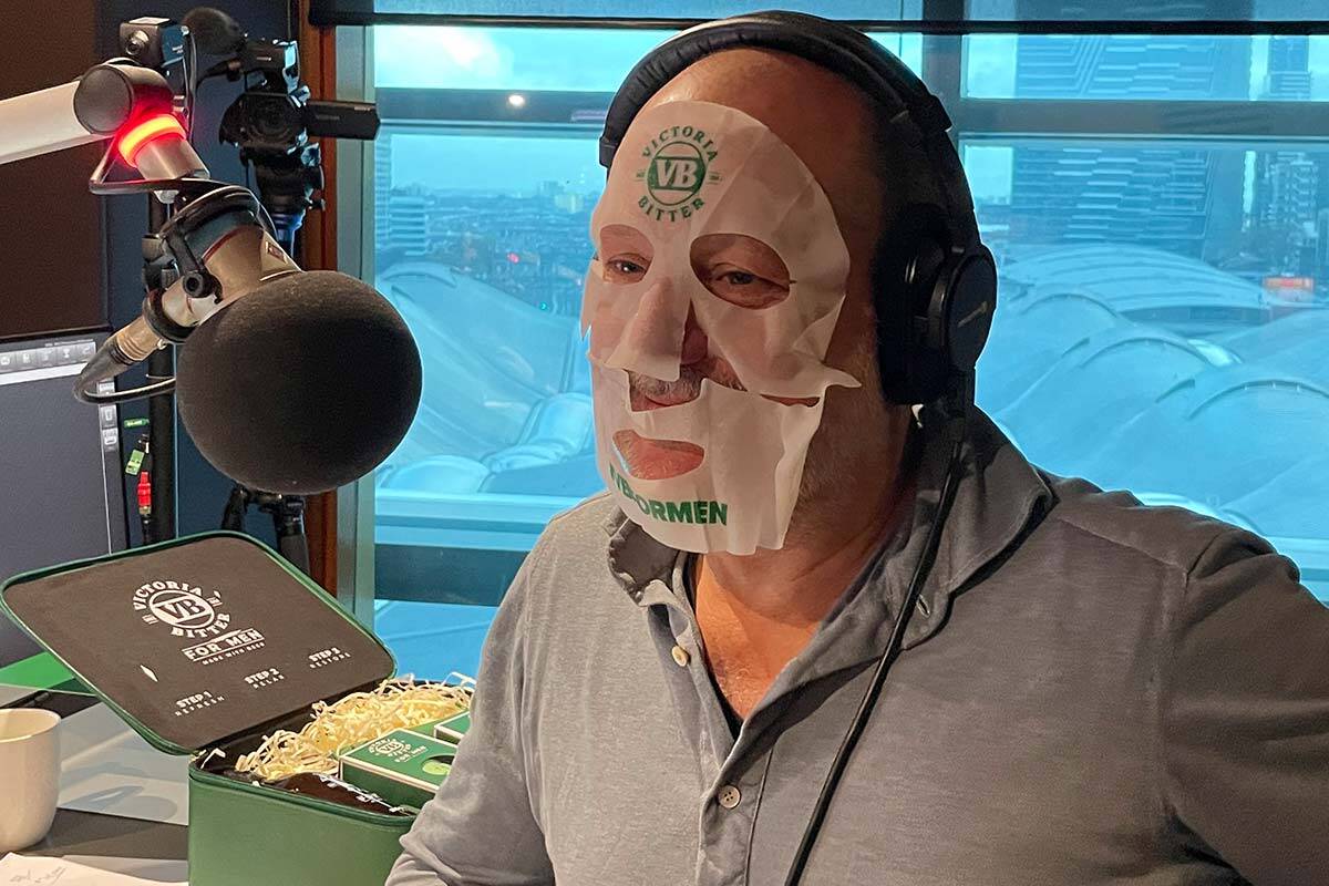 Russ in front of a microphone with a face mask on